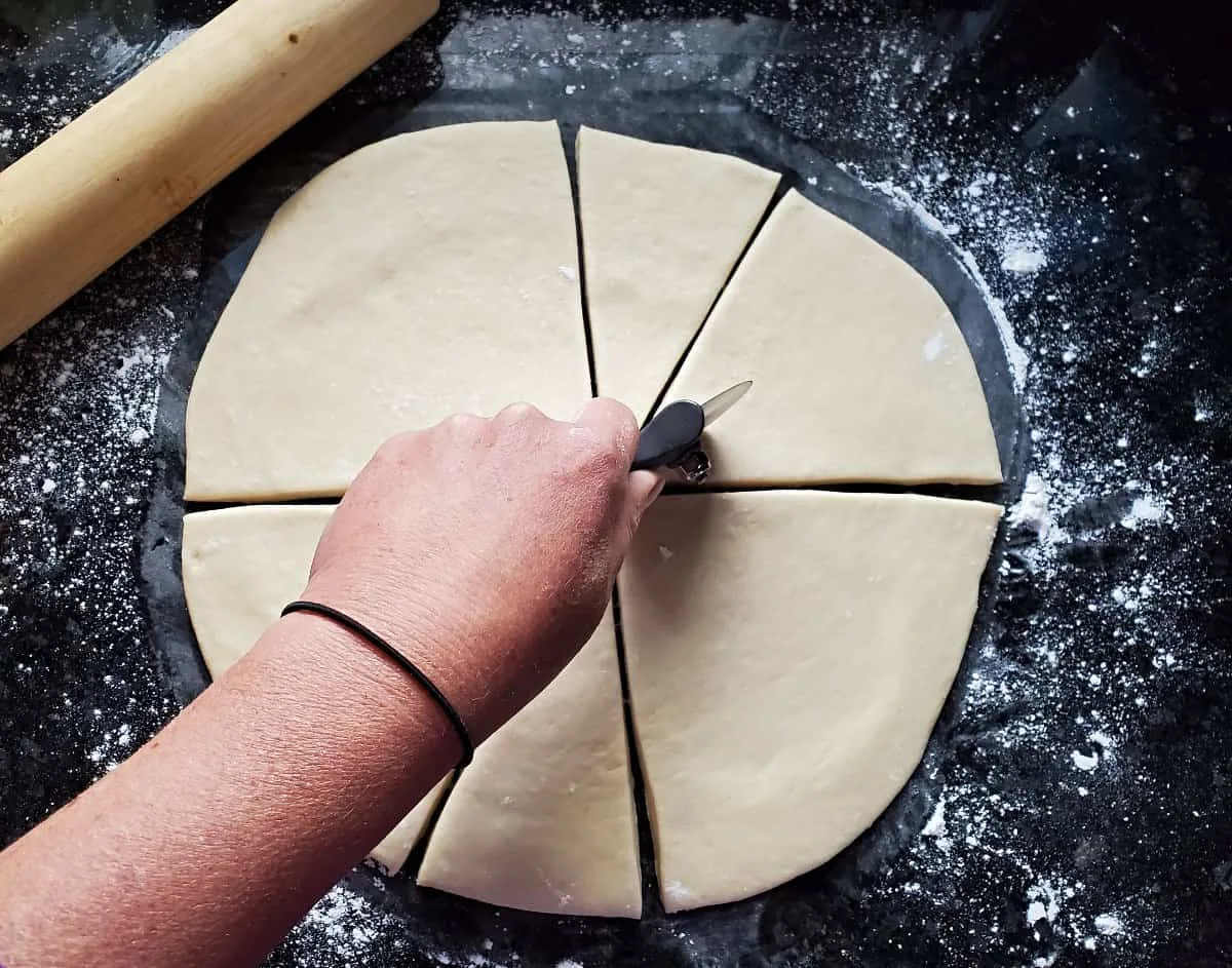 Slicing dough into twelve circles with a pizza cutter.