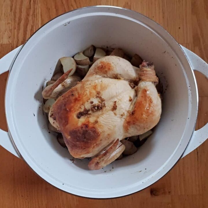 Perfect lemon roast chicken in a white dutch oven.