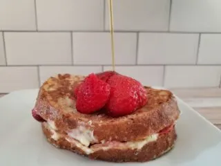 Syrup pouring on stuffed french toast sitting on a white plate.