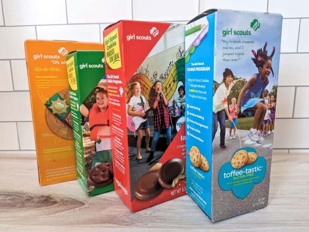 Image shows boxes of Girl Scouts cookie flavors on the wooden counter.