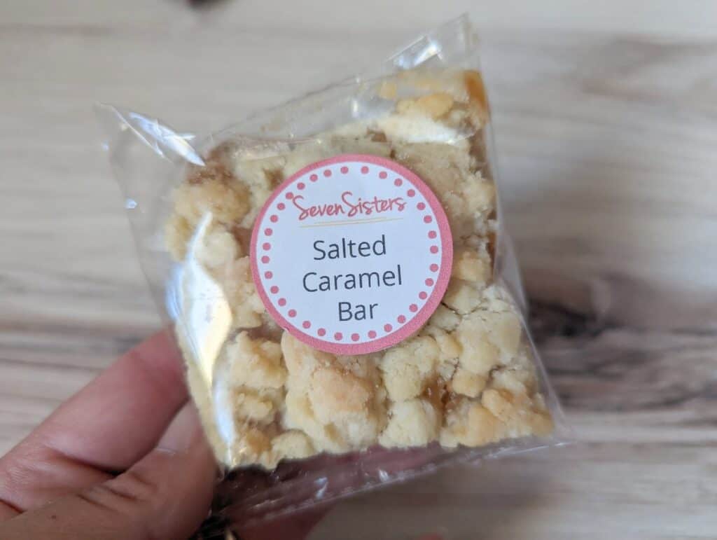 Hand holding a packaged salted caramel bar from Seven Sisters Scones.