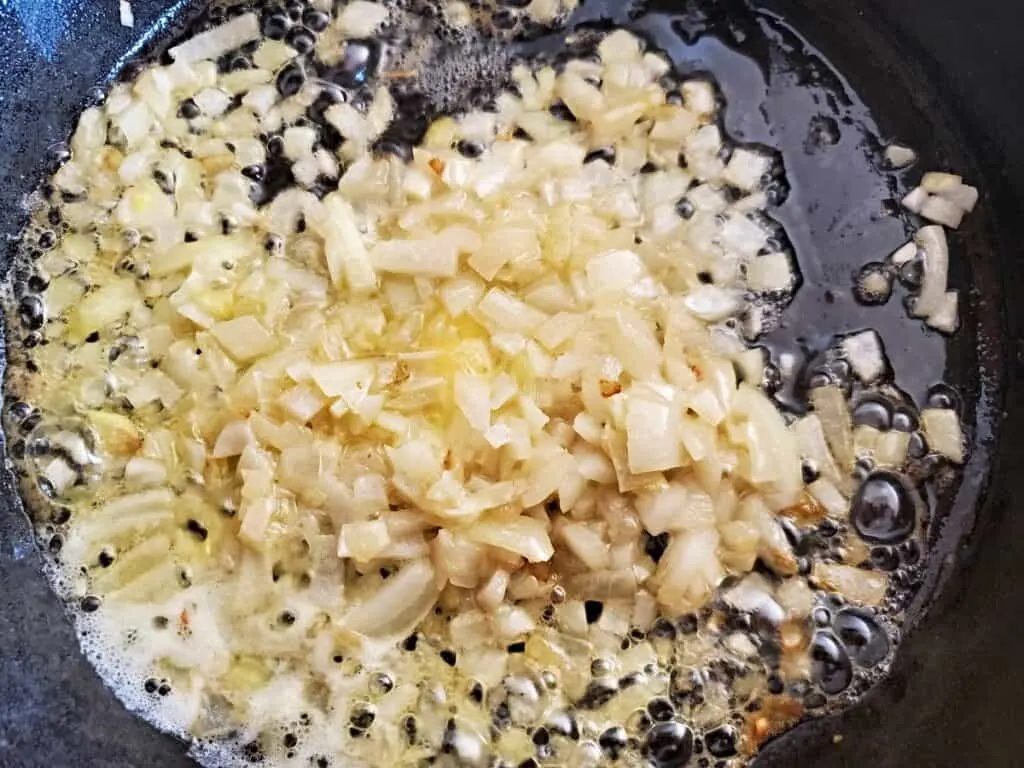 Diced onion cooking in a cast iron skillet.