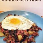 Fried egg and hash on a plate with text homemade corned beef hash.