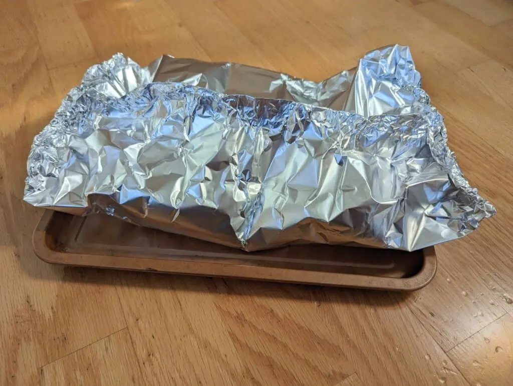 Salmon in a foil tent on a baking pan.