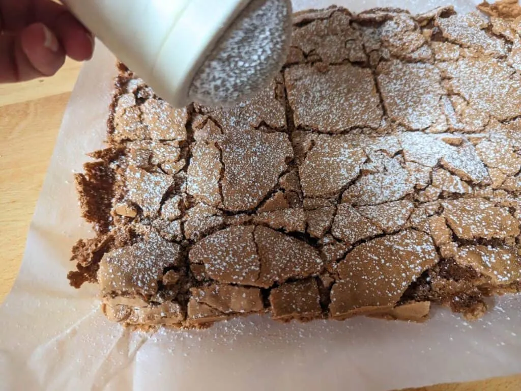 Image shows Adding powdered sugar to brownies.