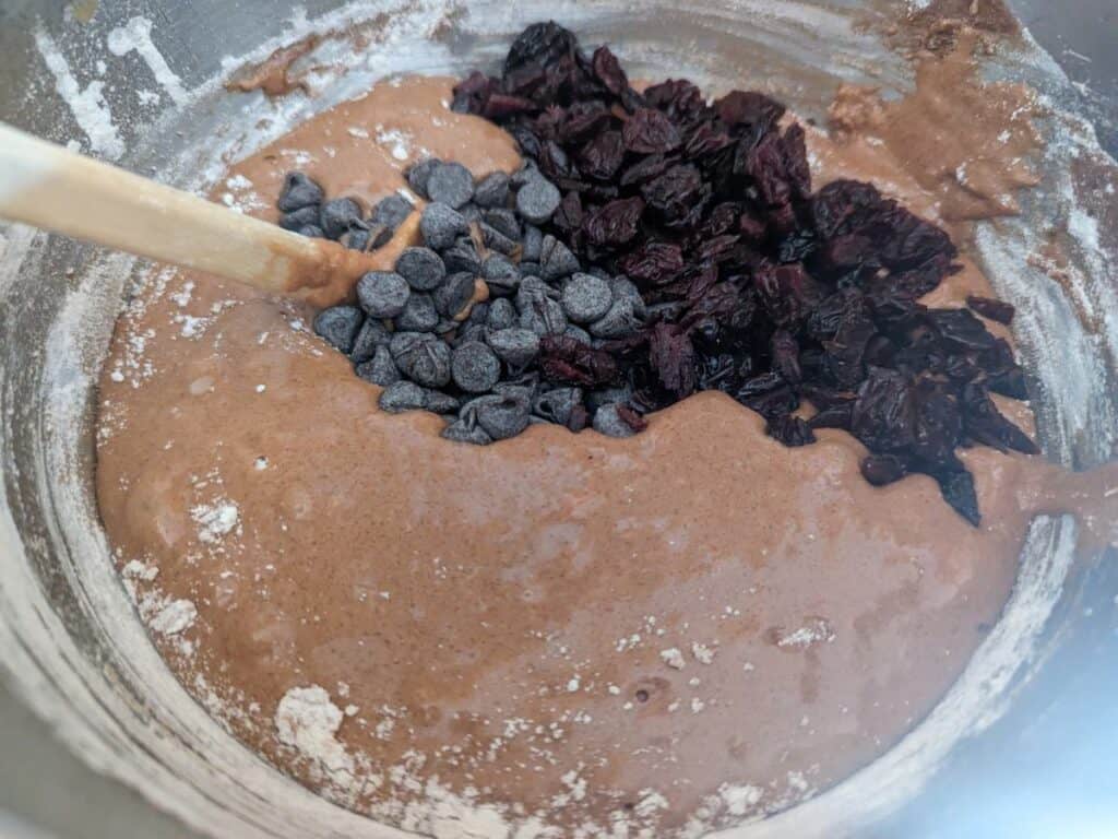 Image shows an Overhead of cherries and chocolate chips in brownie batter.