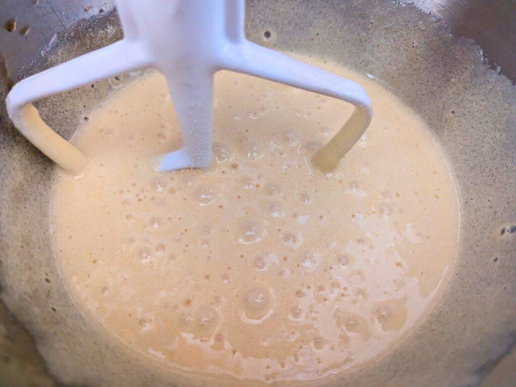 Image shows Whipped eggs and sugar in a mixing bowl.