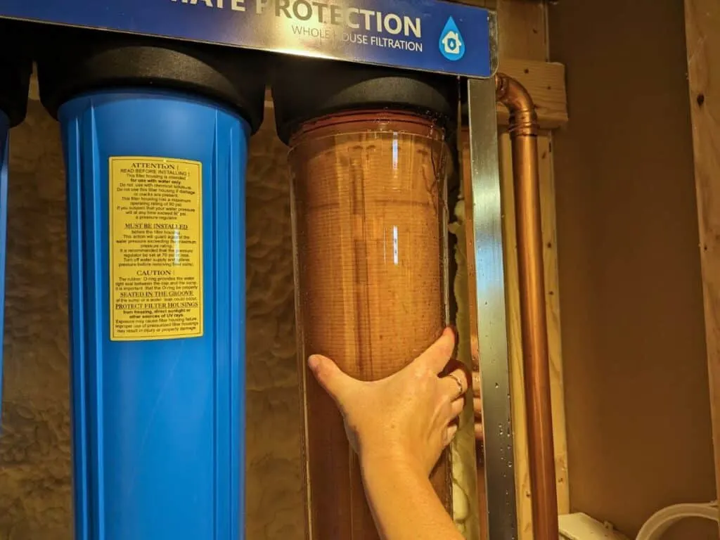 Image shows Loosening a water filter housing by hand.