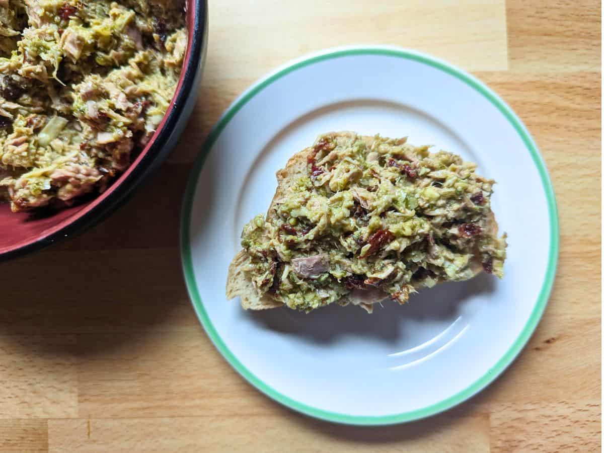 Image shows an overhead shot of an open face Pesto and Sundried Tomato Tuna Salad sandwich.