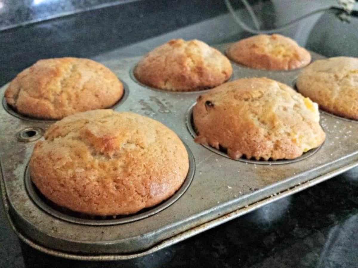 Peach kuchen muffins in a muffin tin.