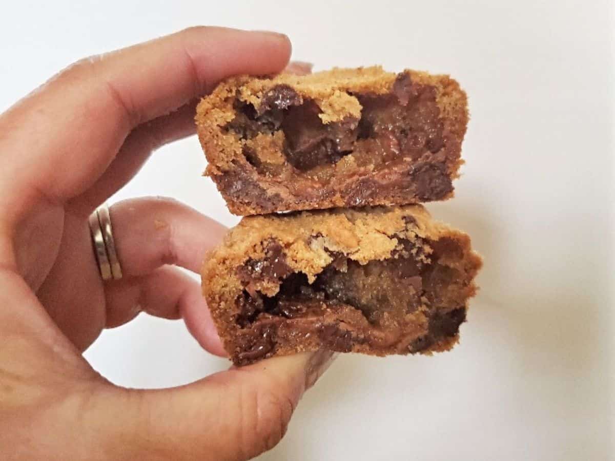 Image shows A person holding up two halves of candy bar stuffed cookies.