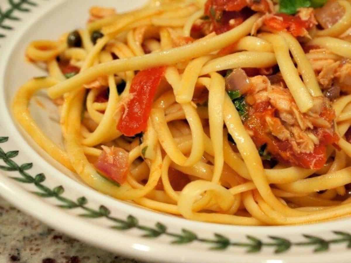 Image shows a closeup view of tuna and tomato pasta in a white patterned bowl.