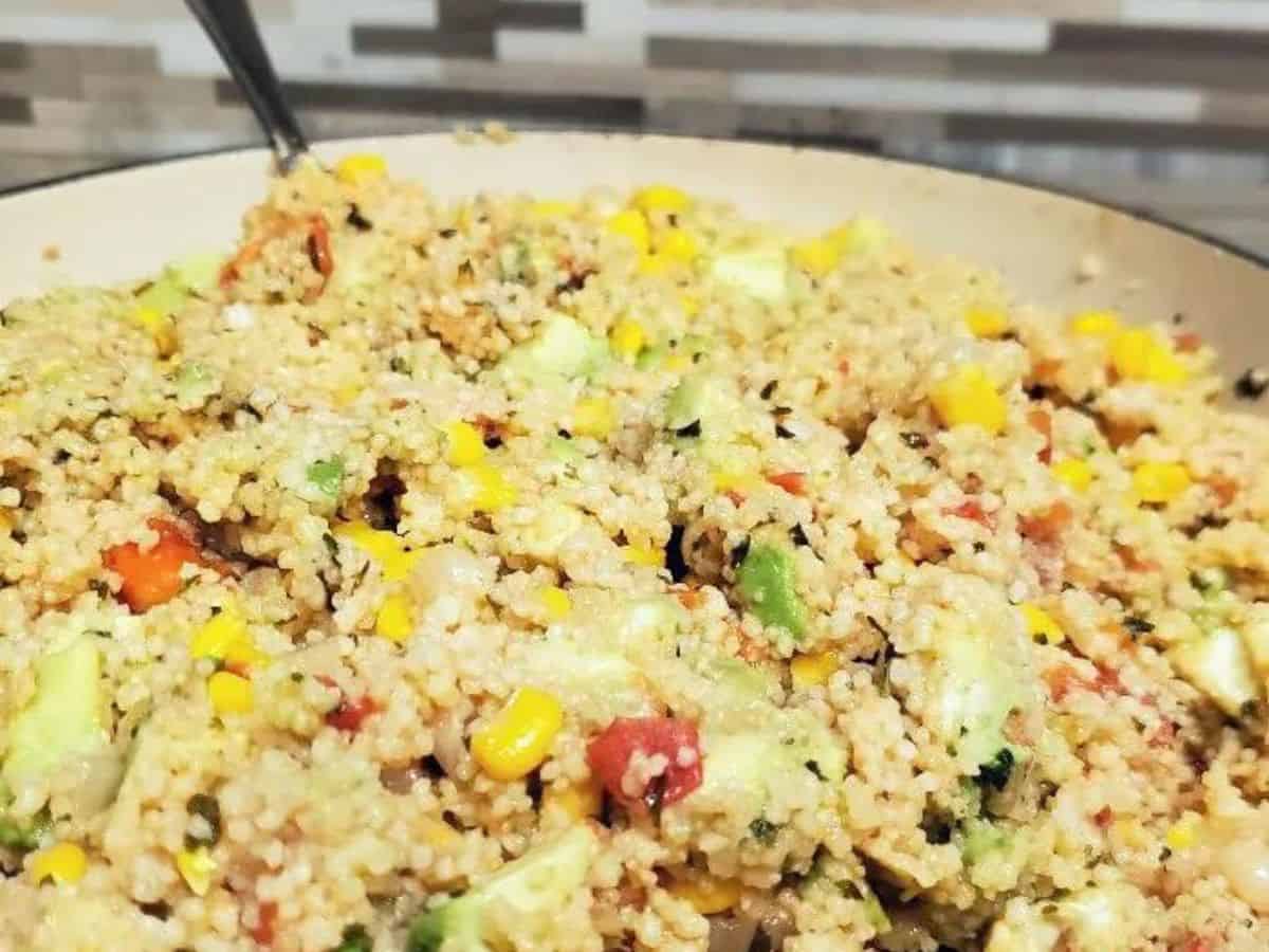 Image shows a closeup of an enameled cast iron pan filled with a vegan couscous salad.