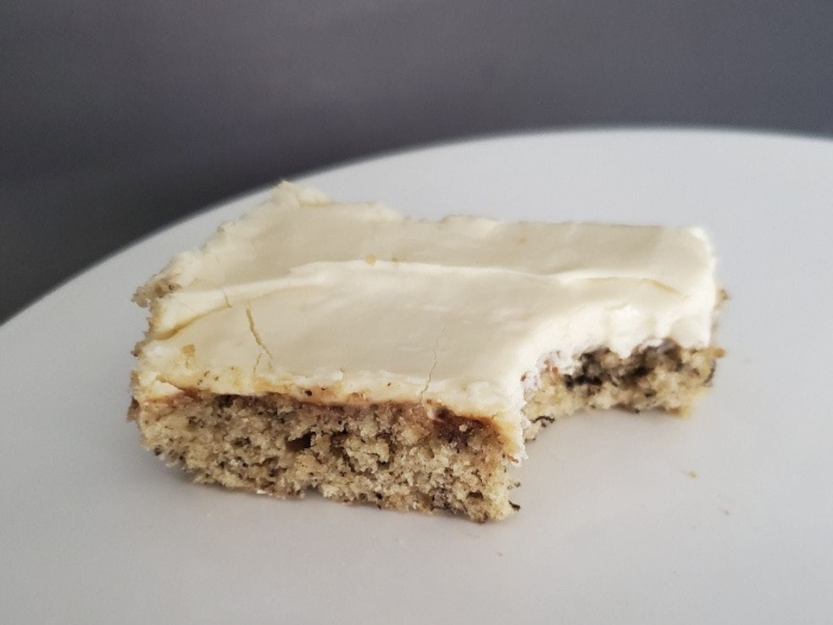 Image shows a Frosted Banana Bar with a bite taken from it on a white plate.