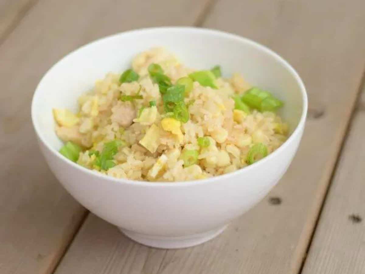 Images shows a white Bowl of chicken fried rice.