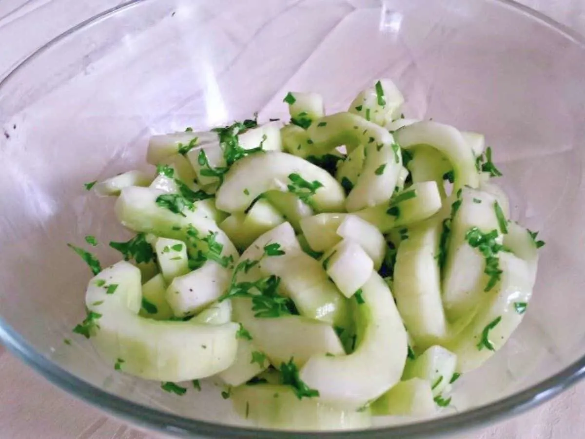 Image shows a close up of a summer Cucumber Salad in a clear bowl.