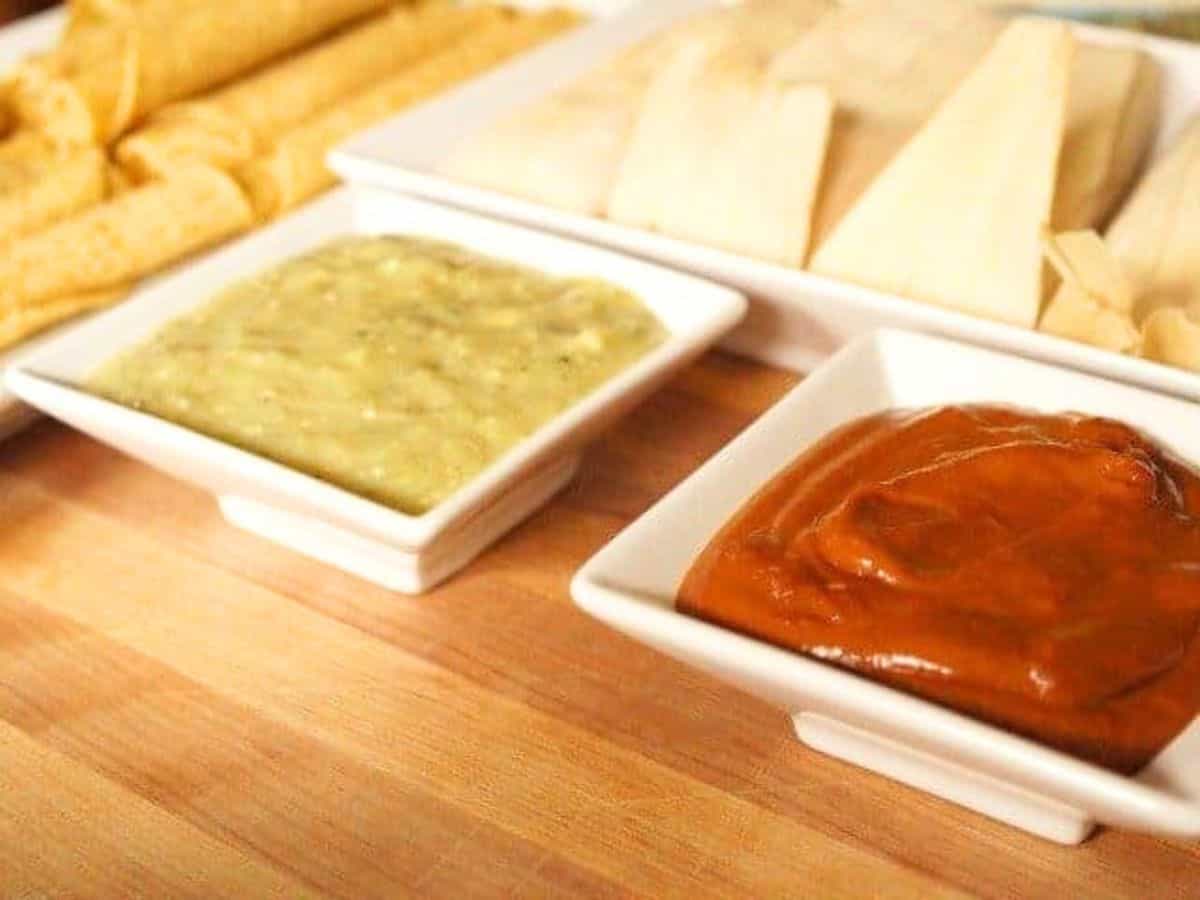 Image shows a taquito dipping into a white bowl of Roasted Tomatillo Salsa.