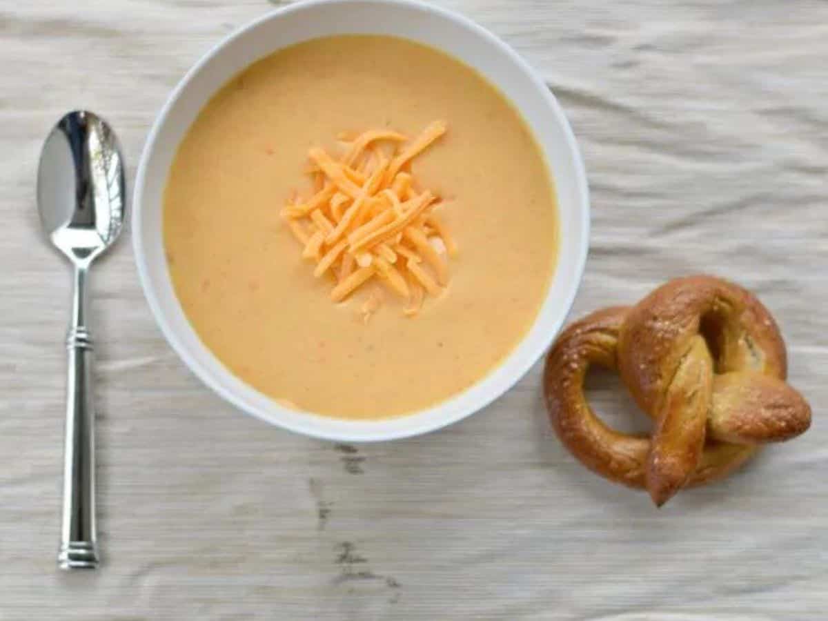 Image shows Pretzel dipping into beer cheese soup.