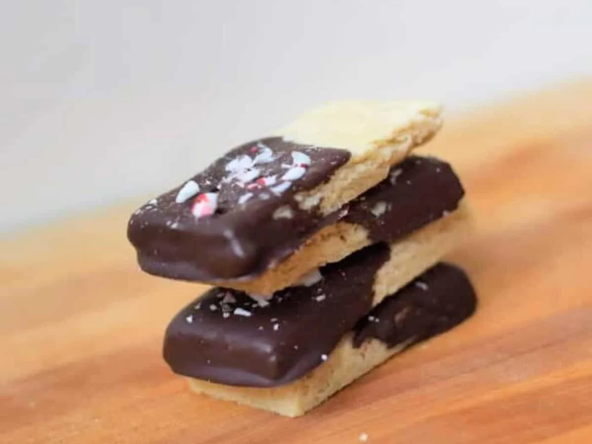 Image shows a stack of four Peppermint Shortbread Cookies on a wooden table.