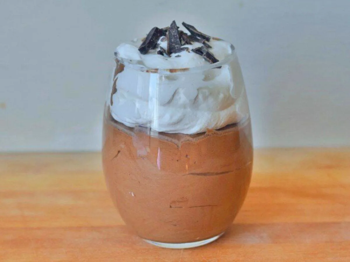 Image shows a Spoon with Baileys chocolate mousse and whipped cream and the full serving behind it.