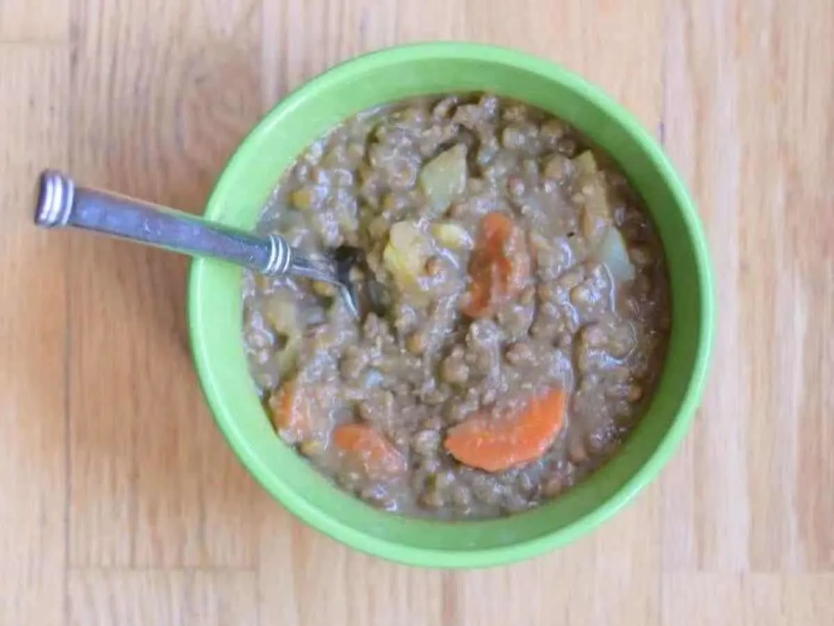 Image shows A bowl of lentil soup with a spoon in it.