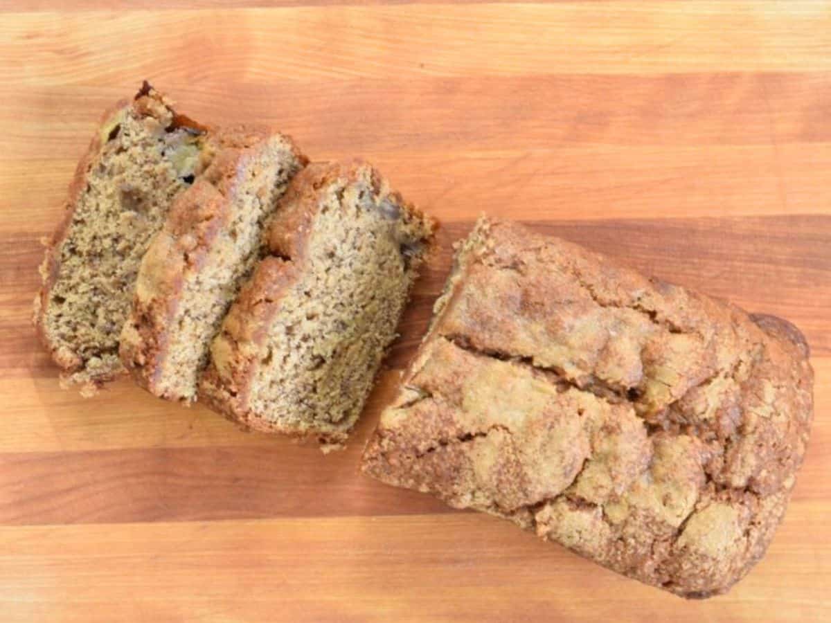 Overhead of brown sugar banana bread partially sliced on a cutting board.