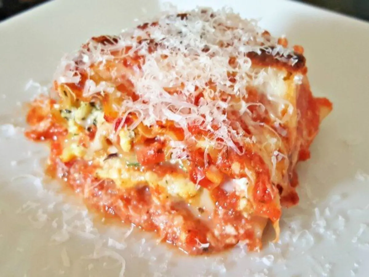 Image shows a lasagna roll up on a white plaet.