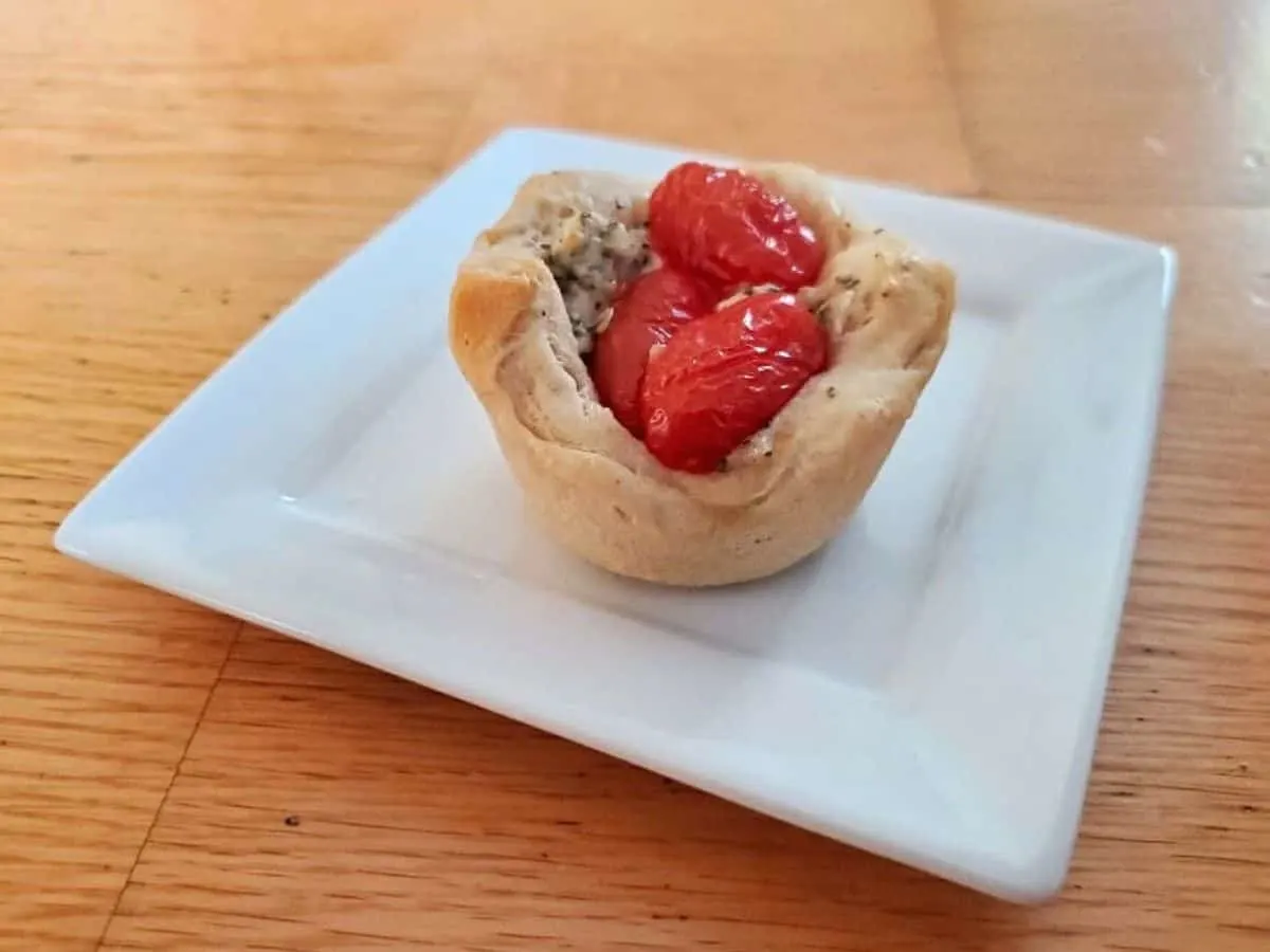 Image shows a Tomato Basil Biscuit Cup on a white plate.