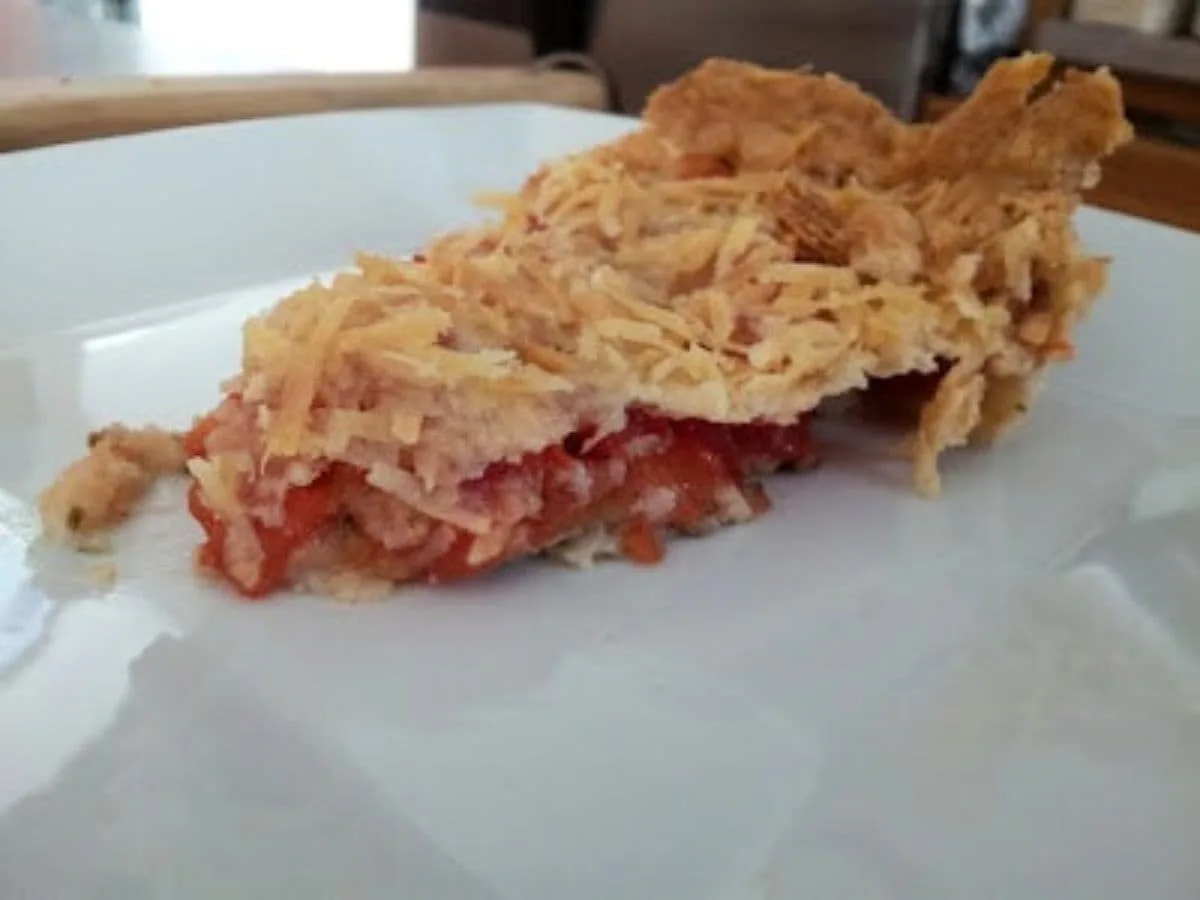 Slice of tomato tart on a white plate.