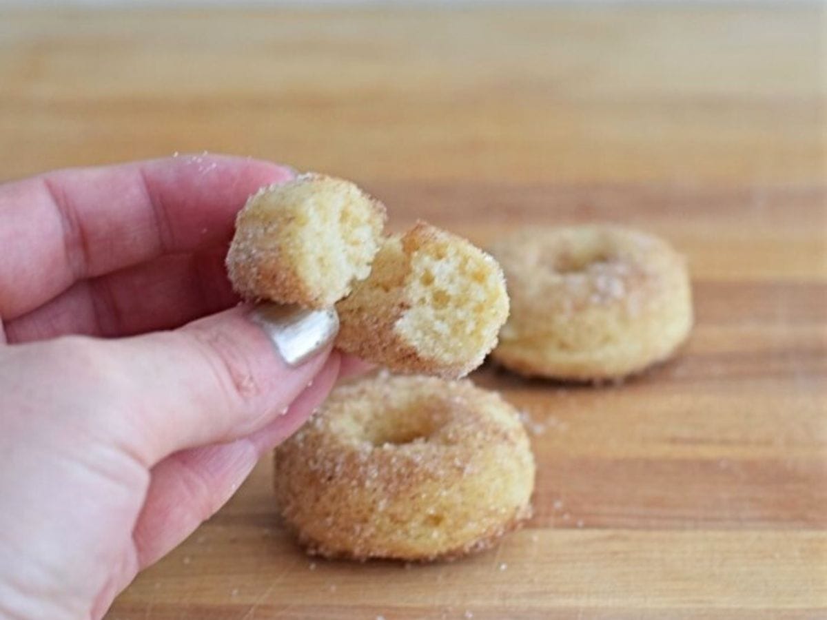 Image shows Baked cinnamon sugar donuts on a wooden table.