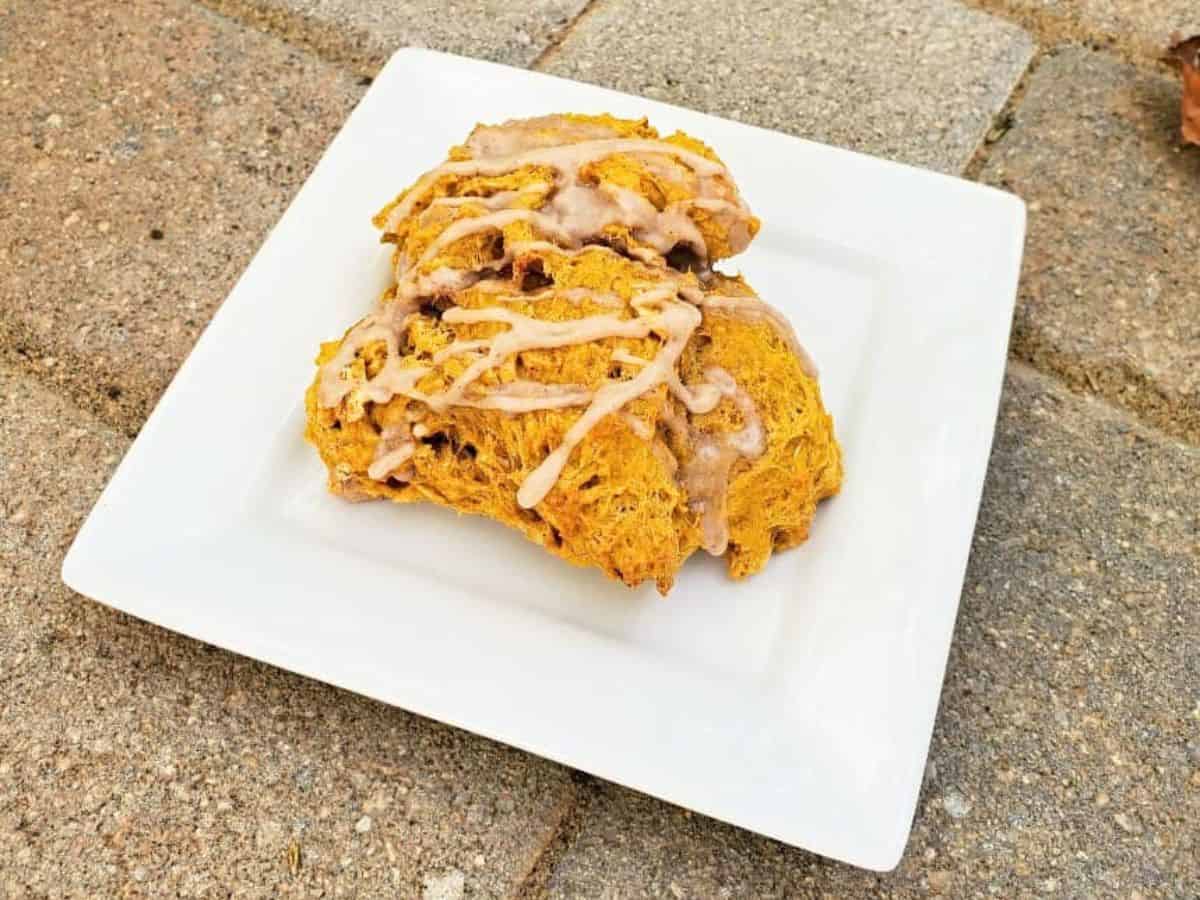 Image shows Three pumpkin scones on a plate with icing.