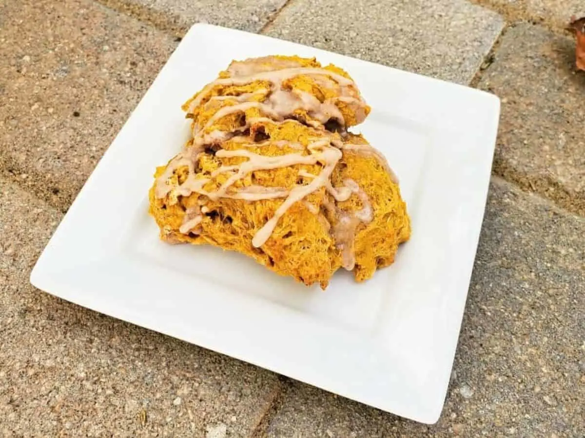 Image shows Three pumpkin scones on a plate with icing.