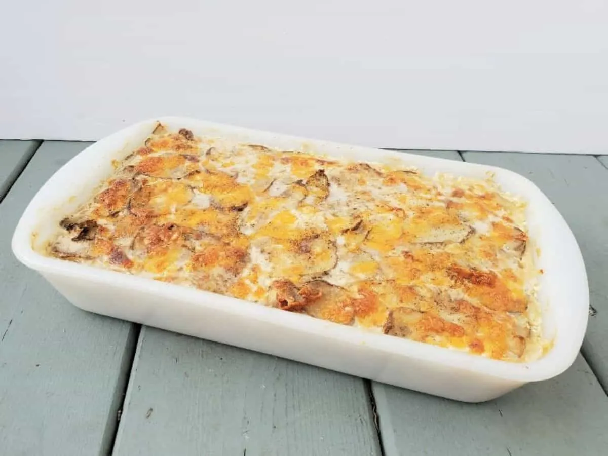 Cheesy scalloped potatoes in a casserole dish on a blue wooden table.