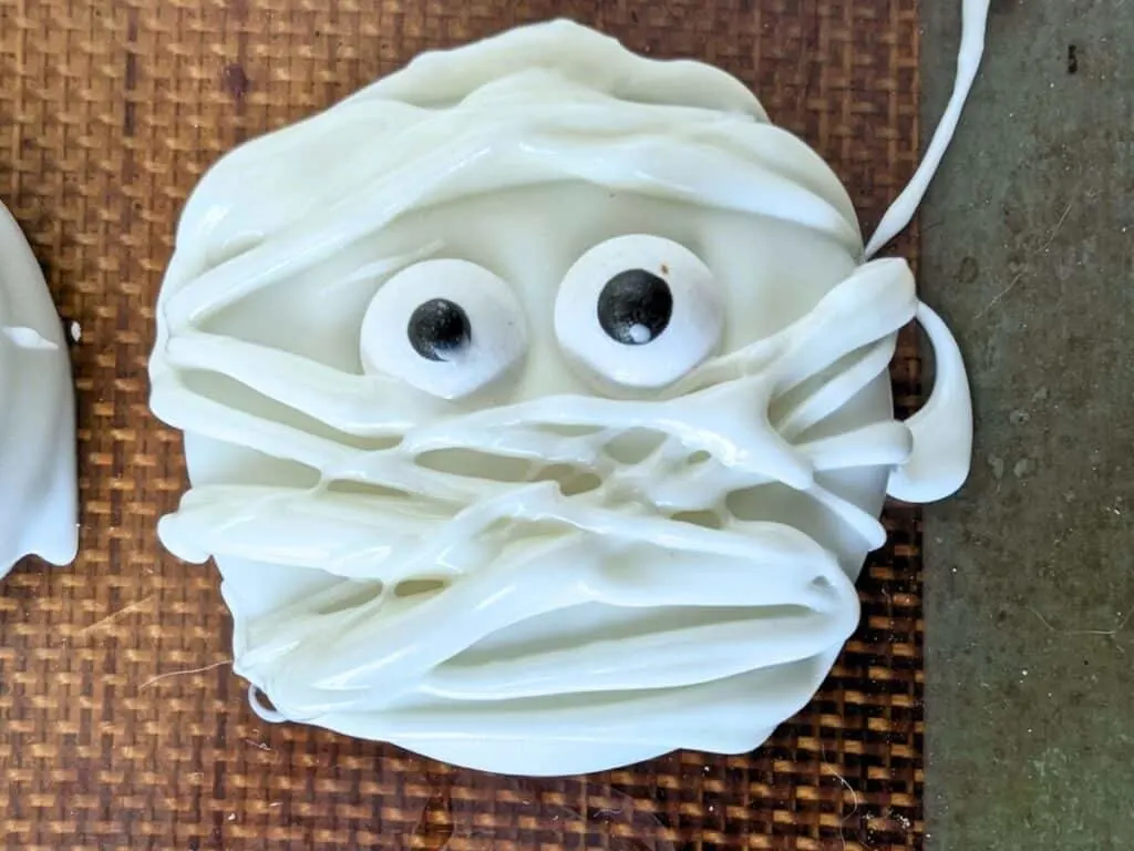 Image shows a Close up of a Halloween oreo mummy cookie on a silpat.