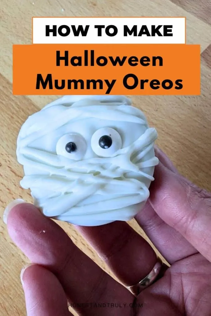 Image shows a Hand holding a mummy cookie with text how to make Halloween mummy oreos.