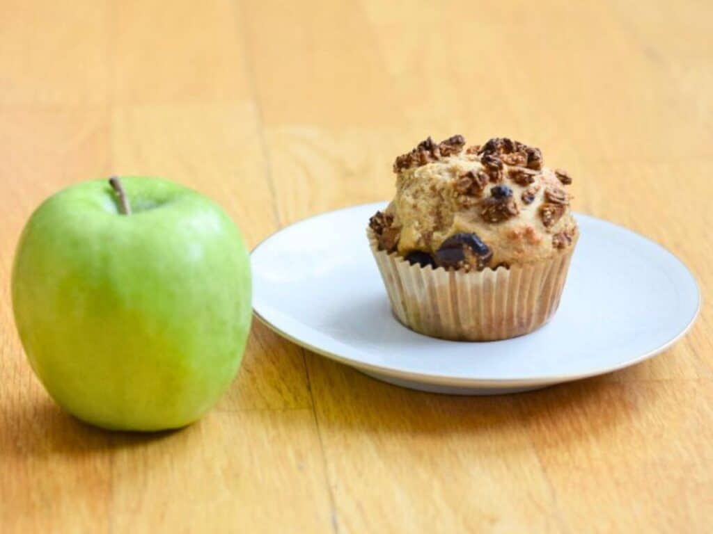 Image shows irresistible apple cinnamon muffin on a plate.