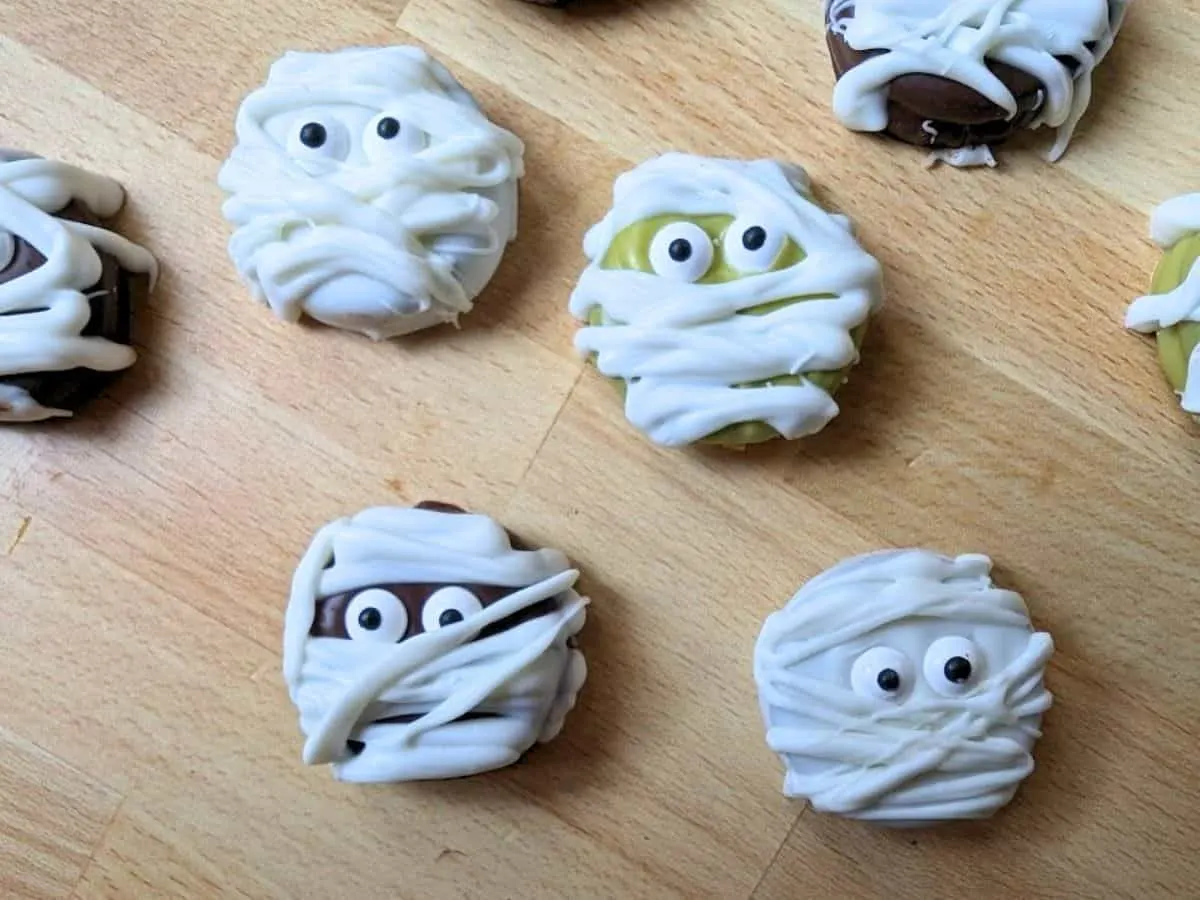 Image shows an Overhead of Halloween mummy cookies on a wooden board.