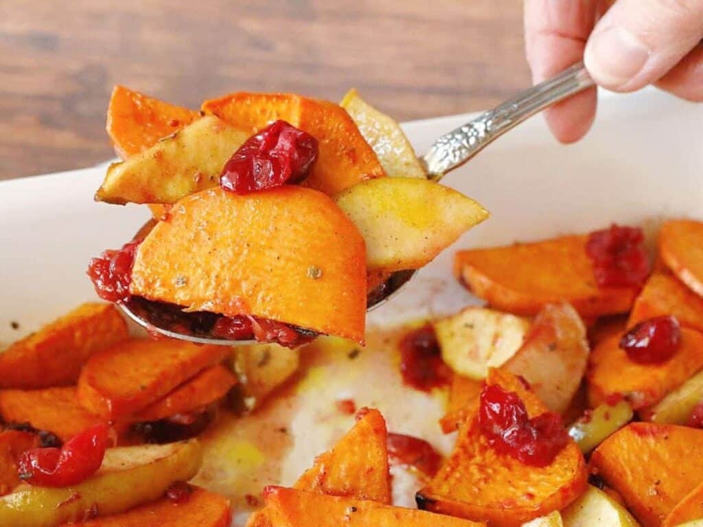 Image shows delicious baked sweet potatoes with apples and cranberries.