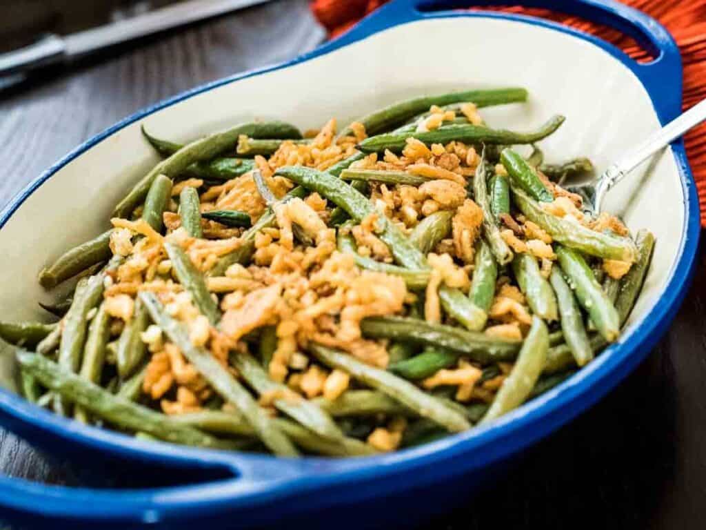 Image shows yummy garlicky green beans with fried onions.