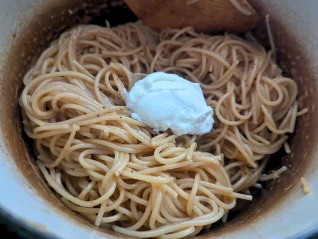 Image shows adding ricotta cheese to the almost-cooked pasta.