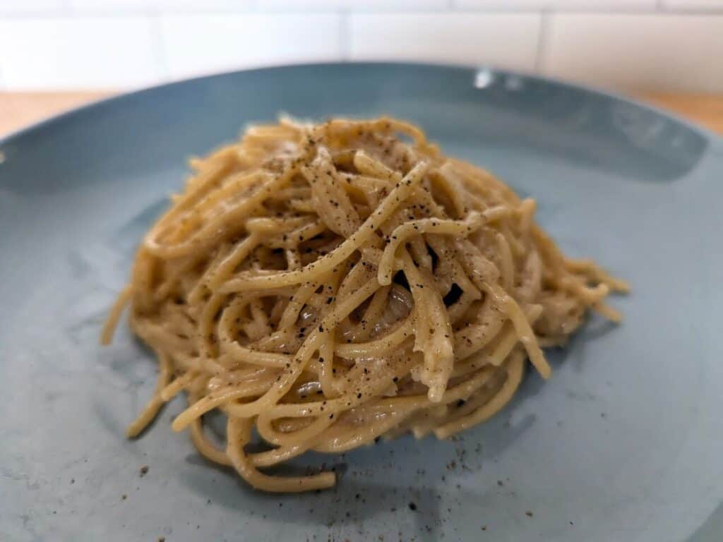 Image shows cooked lemon butter pasta on a blue plate.