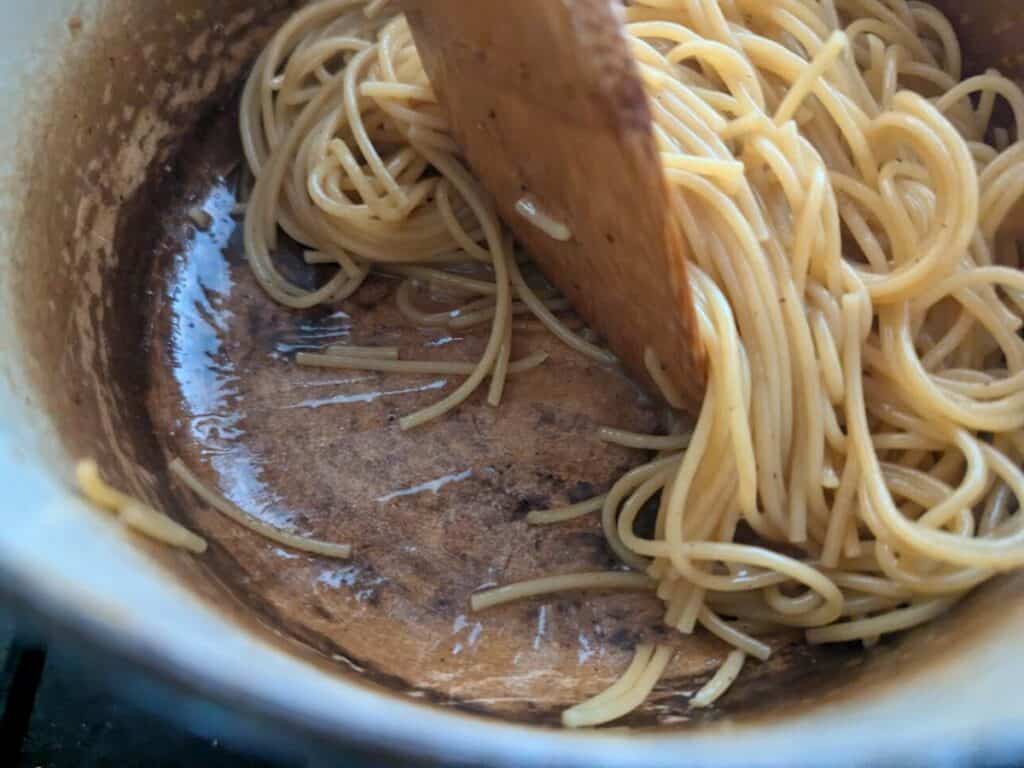 Image shows cooking pasta in a pot with butter.