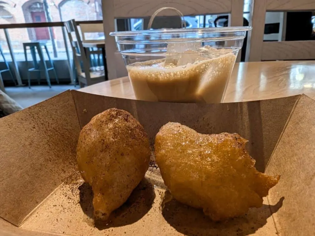 Image shows Loukoumades and greek frappe on a table.