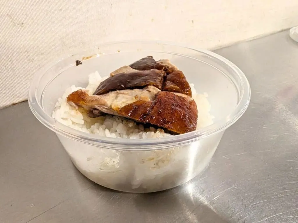 Image shows a small container holding a serving of roast duck over white rice.