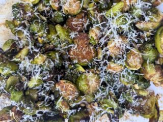 Image shows overhead of roasted brussels sprouts with pine nuts.