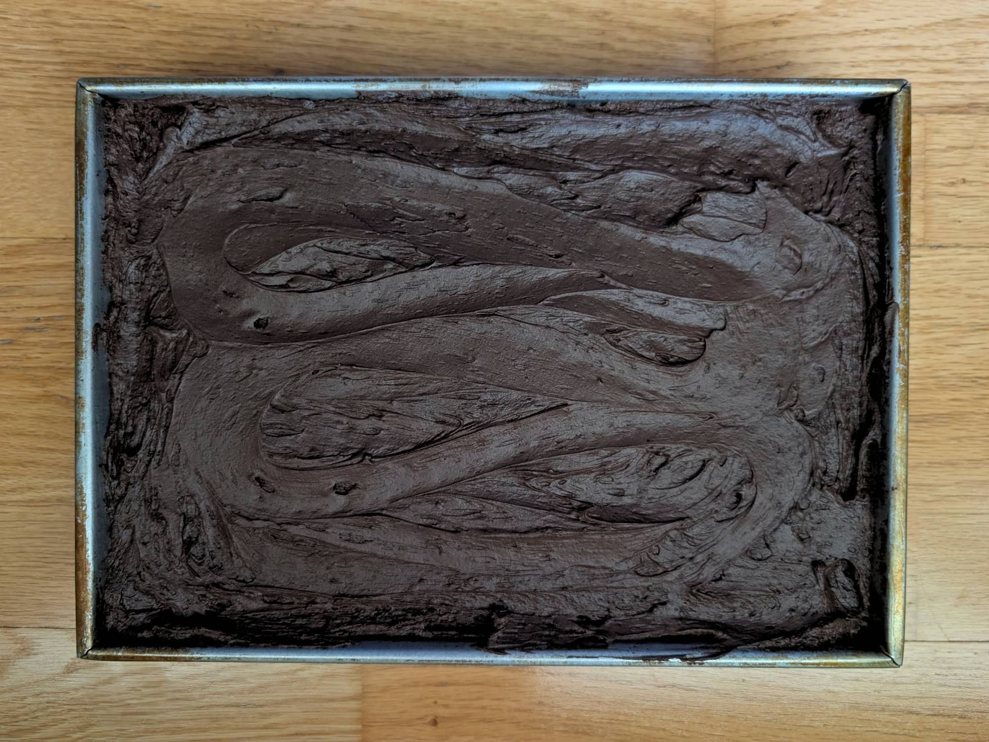 Rectangular metal baking pan filled with frosted chocolate cake.