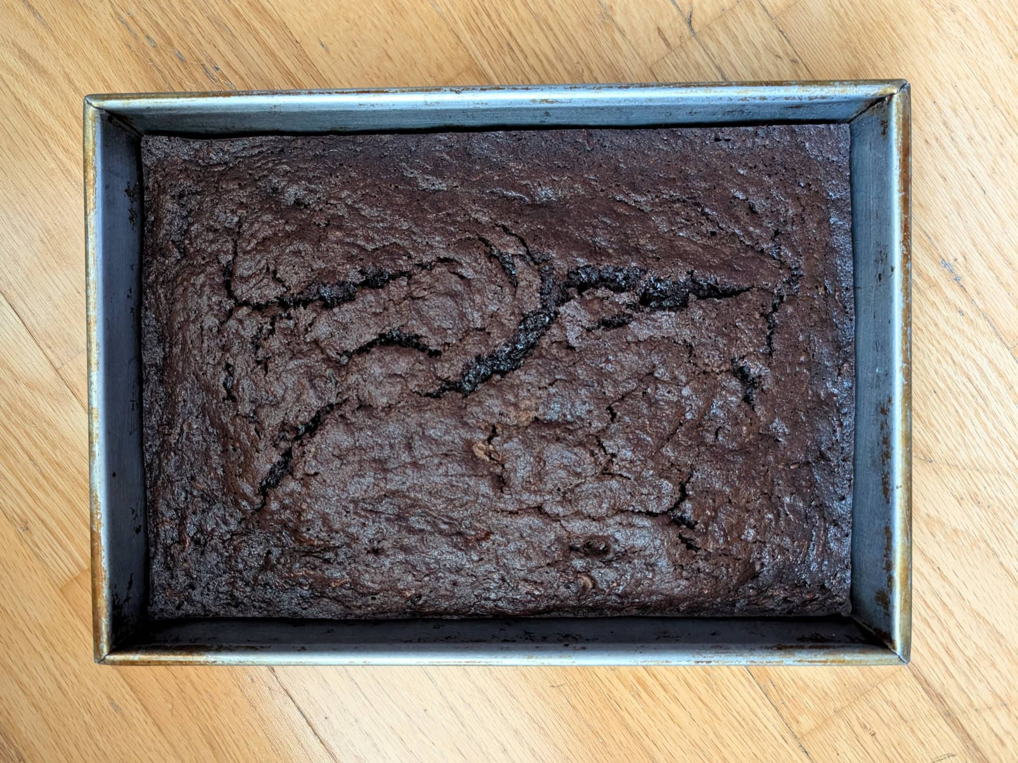 A baked rectangular chocolate cake in a metal baking pan.