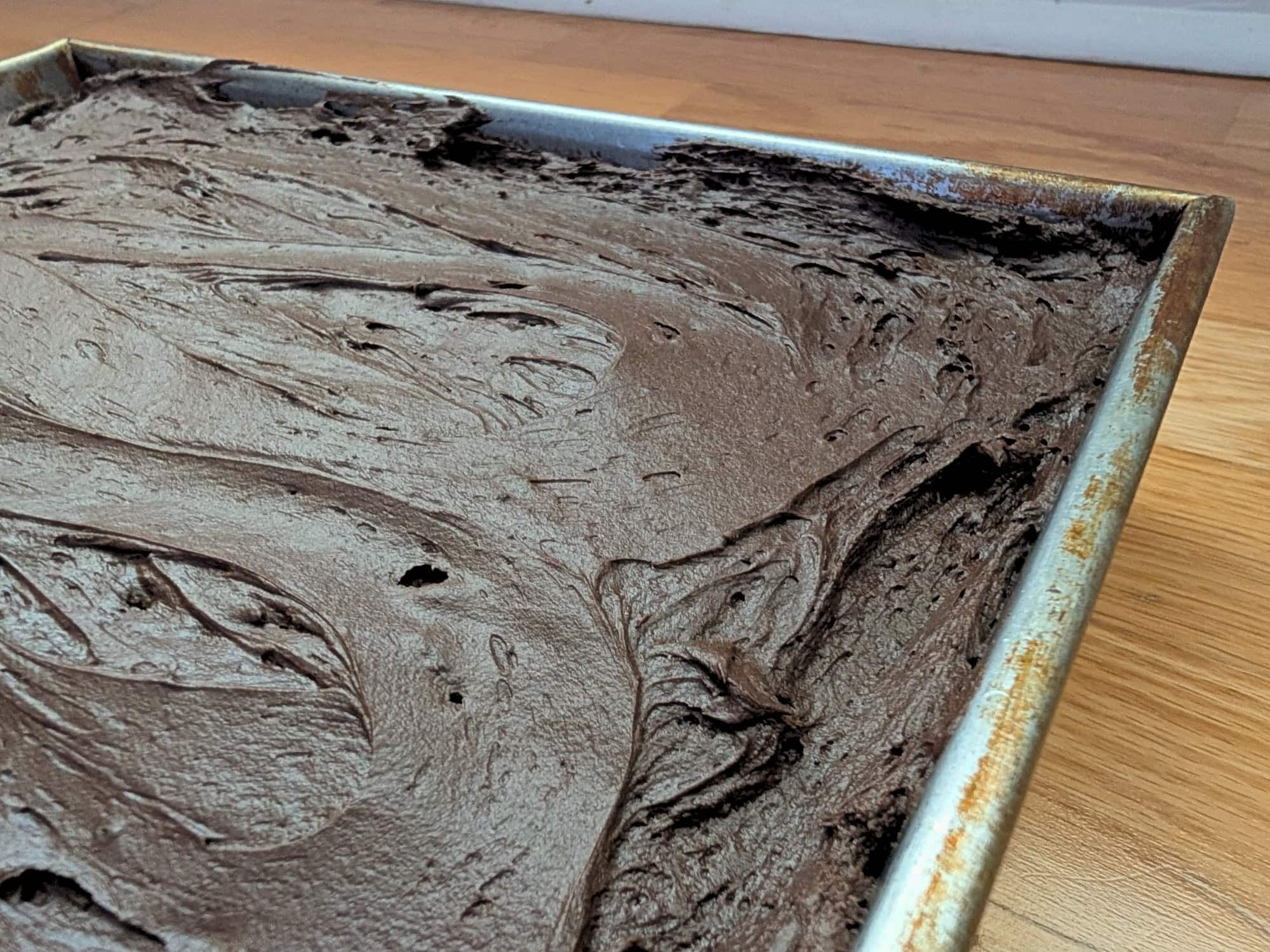 Side view of chocolate zucchini cake with thick chocolate frosting in a 9x13 metal pan.